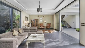 A spacious living area with a sectional sofa, a coffee table, and a large window. - Neo Buana Villa by Betterplace (Canggu)