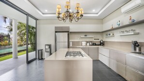 A modern kitchen with a central island, stainless steel appliances, and a chandelier. - Neo Buana Villa by Betterplace (Canggu)