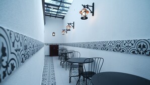 A narrow corridor with patterned walls and a tiled floor, leading to a seating area with tables and chairs. - Mecit Kaptan Konağı (Kastamonu)