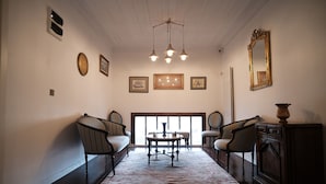 A room with a patterned carpet, a round table with chairs, a sofa, a cabinet, and a large mirror on the wall. - Mecit Kaptan Konağı (Kastamonu)