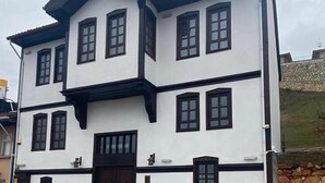 A two-story building with a symmetrical facade, featuring a central entrance with a dark wooden door, flanked by windows on each floor. - Mecit Kaptan Konağı (Kastamonu)
