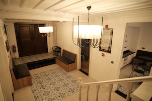 Un vestíbulo de hotel con alfombra estampada, un banco, una araña y una puerta de madera.