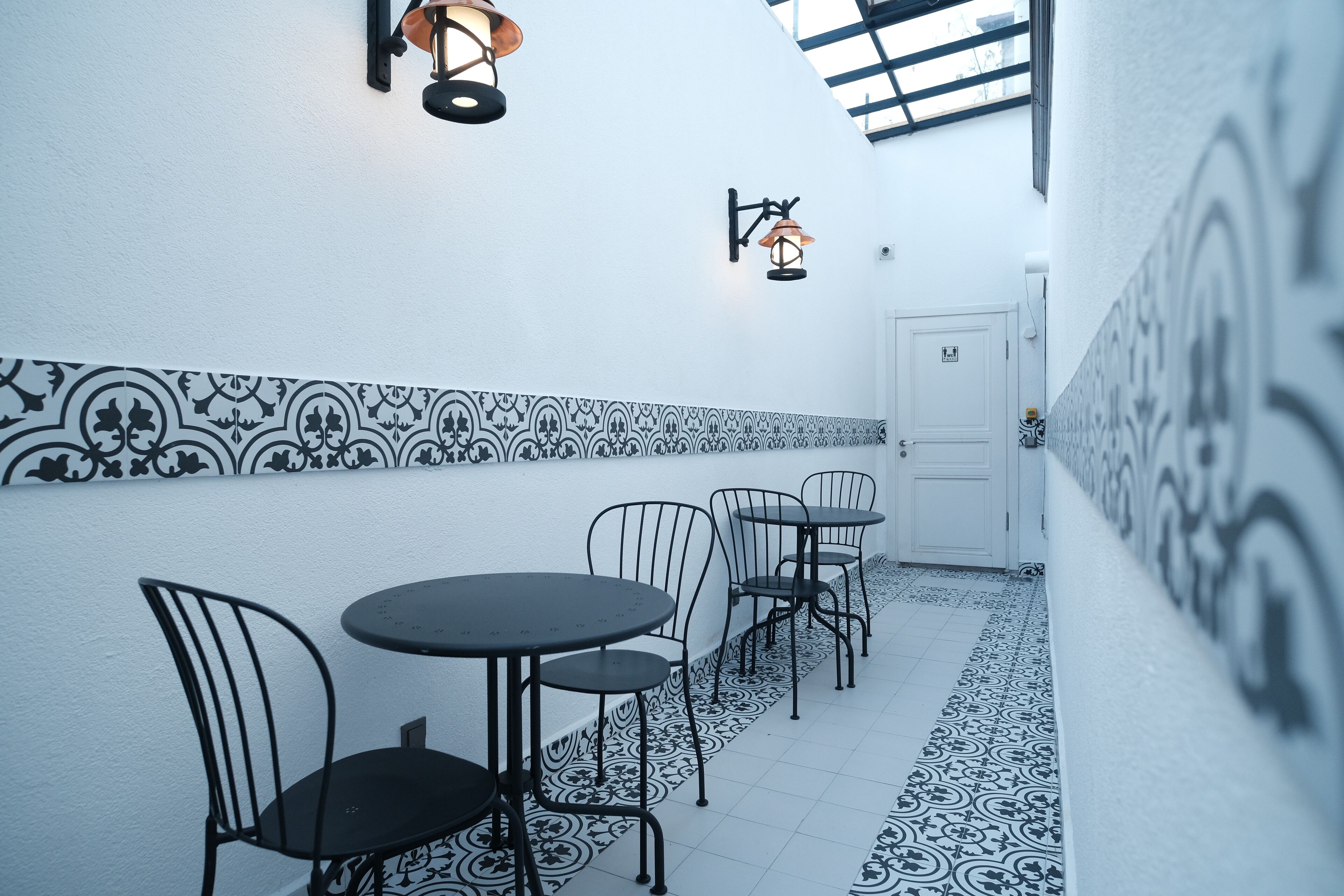 A corridor with patterned walls, a door, and tables with chairs.