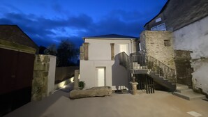 Un bâtiment doté d’une façade en pierre, d’une couleur blanche et d’un escalier menant à un deuxième étage.