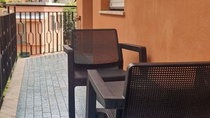 A balcony with two black chairs and a table, a tiled floor, and a view of buildings in the background. - Luna apartment with free parking. (nervi genova)