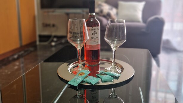 A glass table with two wine glasses, a bottle of wine, and some snacks. - Luna apartment with free parking. (nervi genova)