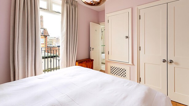 Un dormitorio con cama, armario y ventana con cortinas.