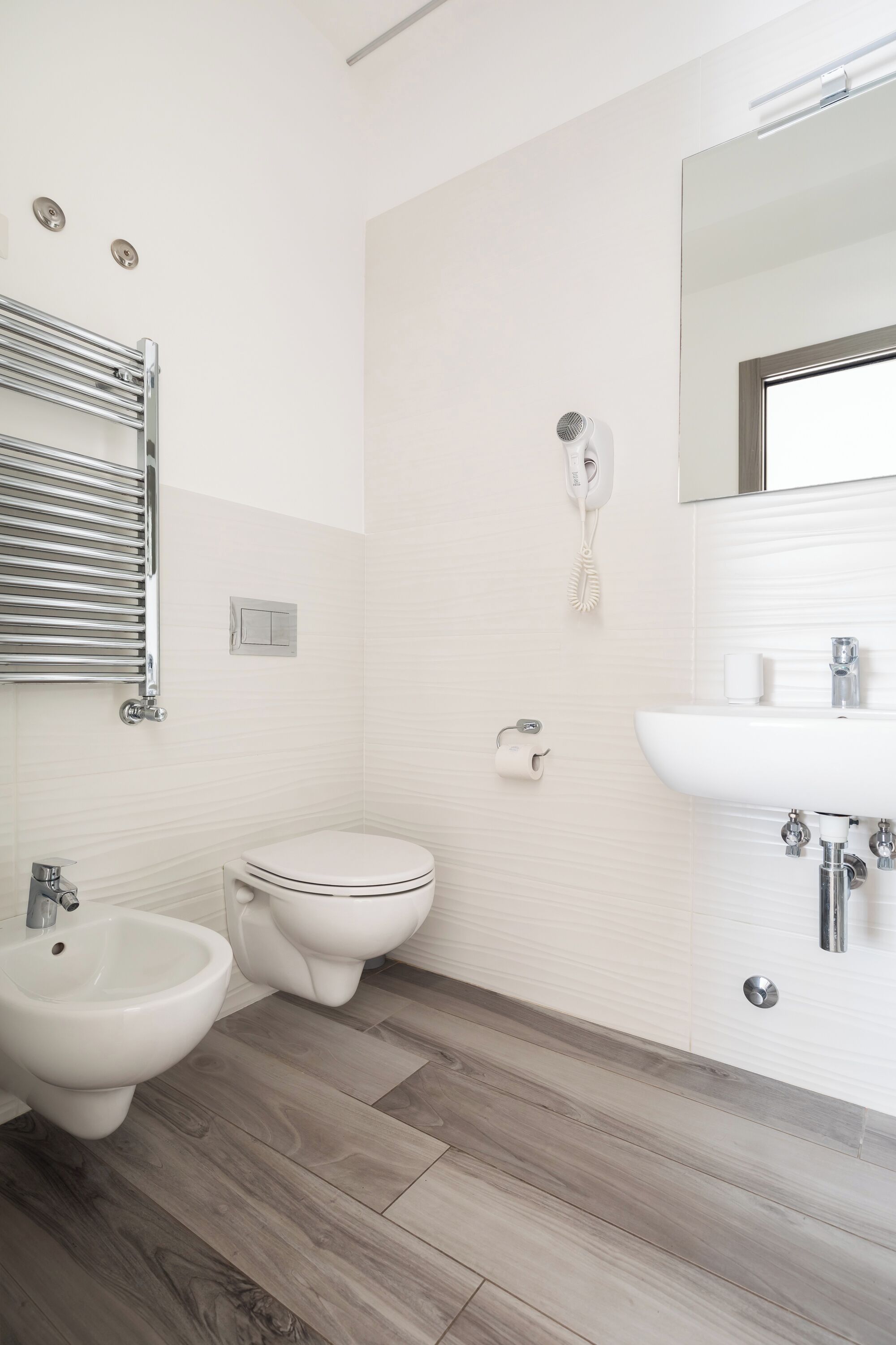 Une salle de bain moderne équipée d’un bidet, de toilettes et d’un lavabo.