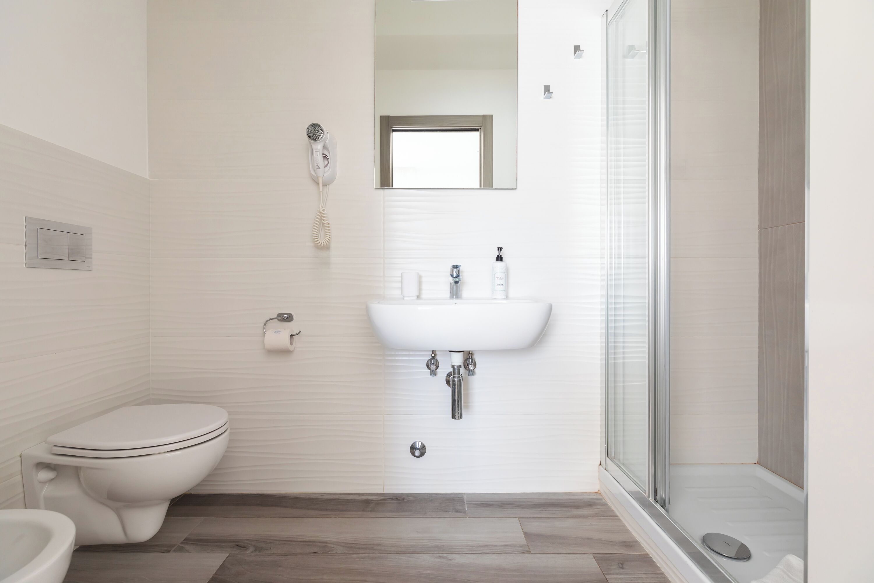 Ein modernes Badezimmer mit Toilette, Waschbecken und Dusche.