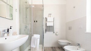 Ein modernes Badezimmer mit einer Duschkabine aus Glas, einem großen Waschbecken, einem Bidet und einer Toilette.