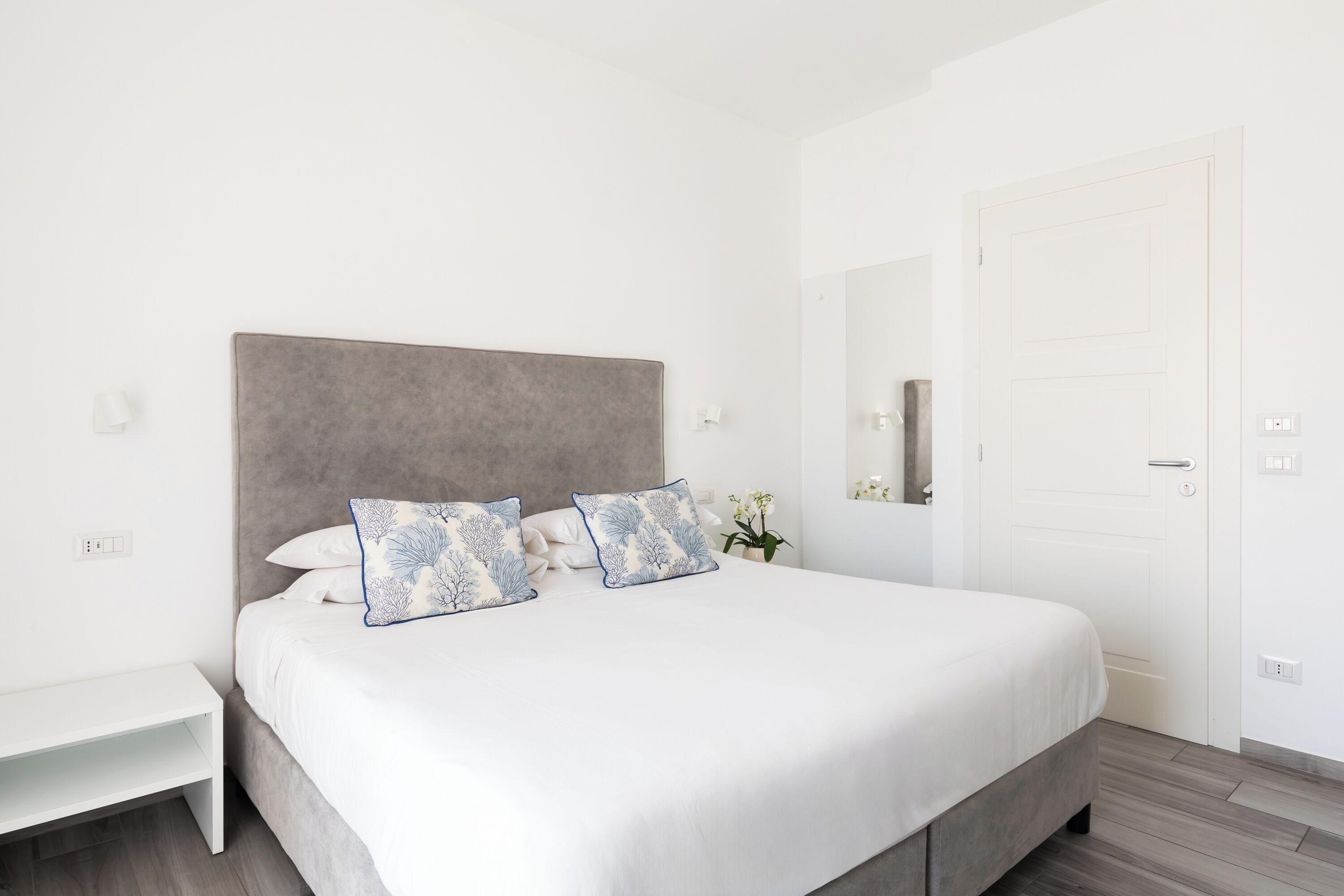 Un dormitorio ordenado con una cama grande, una mesita de noche y una puerta.
