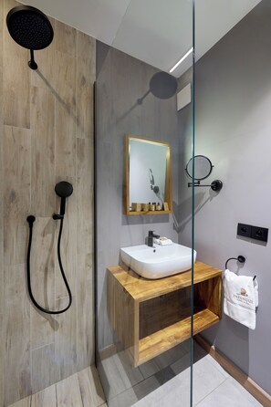 A modern bathroom with a glass shower enclosure, a wooden vanity, a white sink, and a mirror with a gold frame. - PAPANGUE Hôtel & Spa (L'Étang-Salé)