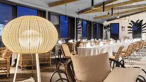 A dining area with wicker chairs and tables, wooden beams on the ceiling, and large windows. - PAPANGUE Hôtel & Spa (L'Étang-Salé)