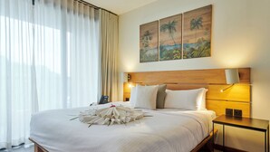 A spacious bedroom with a large bed, a ceiling fan, a bedside table with a lamp, and a painting on the wall. - PAPANGUE Hôtel & Spa (L'Étang-Salé)