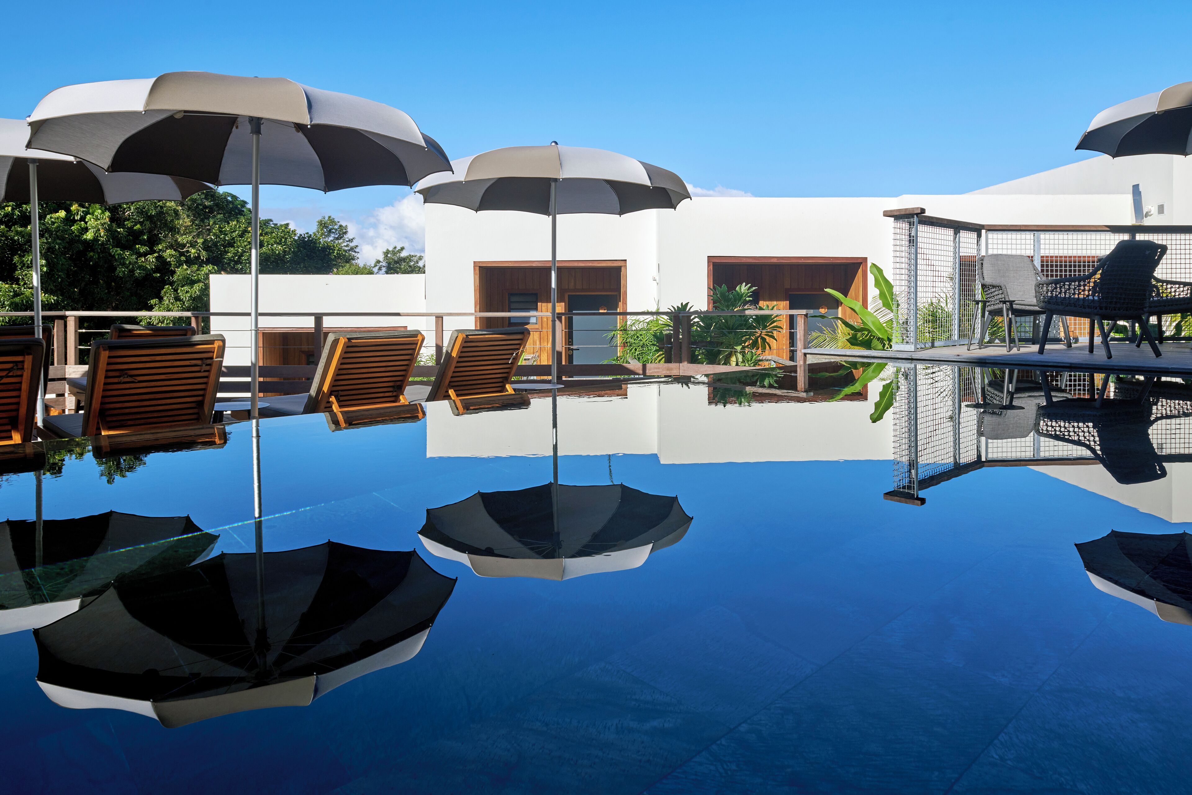 A poolside area with umbrellas, lounge chairs, and a modern building with large windows.