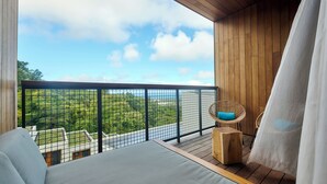 A balcony with a view of greenery and a body of water, wooden flooring, a bed, and two wicker chairs. - PAPANGUE Hôtel & Spa (L'Étang-Salé)
