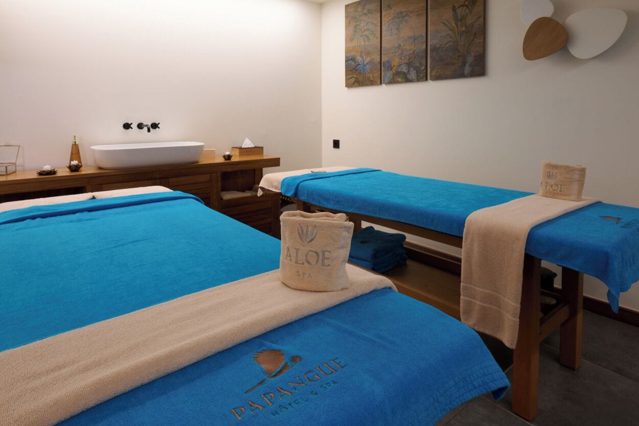 Um quarto de spa com duas camas, uma pia e uma mesa de madeira.