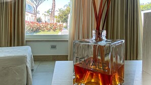 A room with a bed, a window with curtains, and a bottle of perfume on a table. - Female Resort (San Felice Circeo)