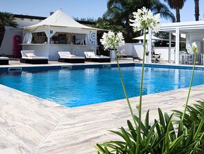 A pool area with lounge chairs, a bar, and a covered seating area. - Female Resort (San Felice Circeo)