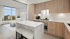 Een moderne keuken met marmeren aanrechtbladen, houten kastjes en een groot raam met uitzicht over de stad.