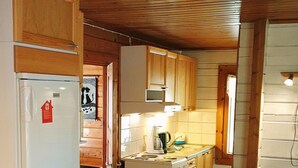 A compact kitchen with wooden cabinets, a refrigerator, a stove, and a microwave.