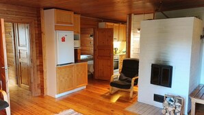 A cozy cabin interior with wooden floors, a kitchenette, a fireplace, and a comfortable seating area.