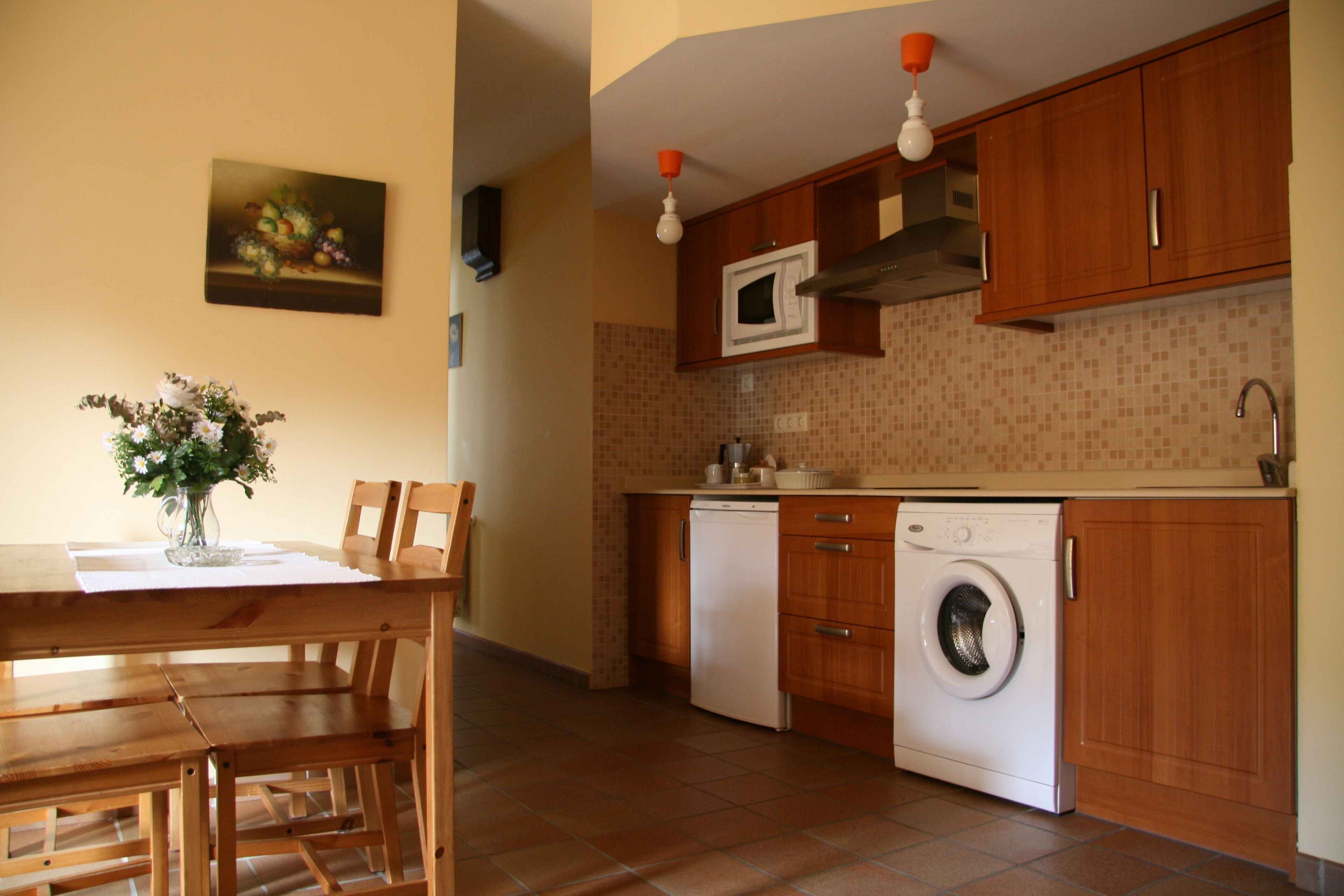 A kitchen with wooden cabinets, a microwave, a dishwasher, and a washing machine.