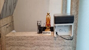 A reception desk with a marble countertop, a statue, and a printer. - Tanvi Guest House (Mumbai)