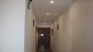 A narrow hallway with wooden flooring and white walls. - Tanvi Guest House (Mumbai)