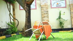 A metal chair with an orange cloth, a tree, and a hotel sign in the background. - GLORY SUMMIT HOTEL  (Hoima)
