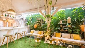 A cozy indoor space with a bar area, seating, and lush greenery. - Buddha Beach Thoiry  (Thoiry)