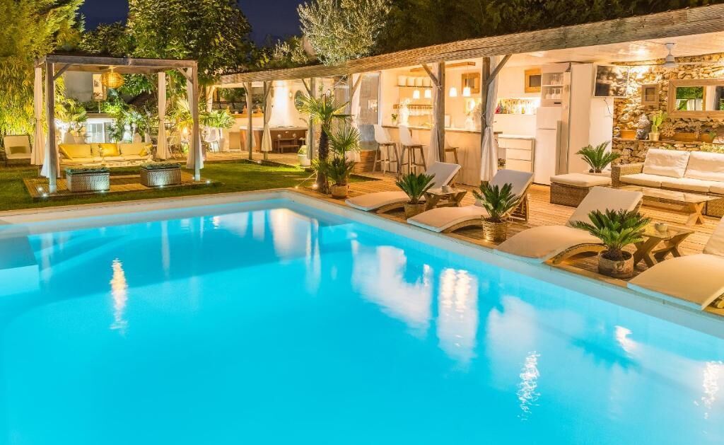 A well-lit outdoor pool area with lounge chairs and a covered seating area.