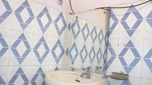 A bathroom with a sink, mirror, and blue diamond-patterned tiles. - Hotel Ambika Palace by Shiwani Associate (Agra)