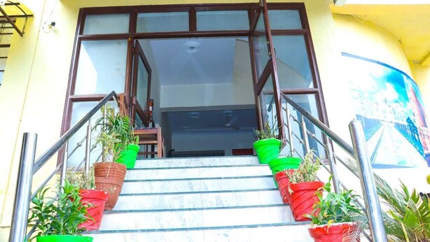 A staircase with potted plants leading to a door with glass panels. - Hotel Ambika Palace by Shiwani Associate (Agra)