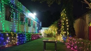 A house with colorful lights on the exterior walls and a small table in the yard. - Hotel Ambika Palace by Shiwani Associate (Agra)