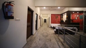 A hotel corridor with a fire extinguisher, a reception desk, and a staircase. - Hotel Ambika Palace by Shiwani Associate (Agra)