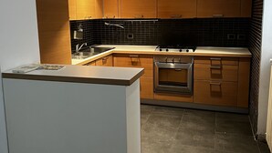 A modern kitchen with wooden cabinets, a central island, and a black tiled backsplash. - Loft in downtown Milan, cozy, quiet 15 minutes from p.zza Duomo. (Milano)