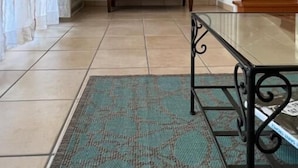 Ein Zimmer mit einem hölzernen Schminktisch, einem flachbildfernseher darüber montiert, einem Glastisch und einer Treppe rechts.
