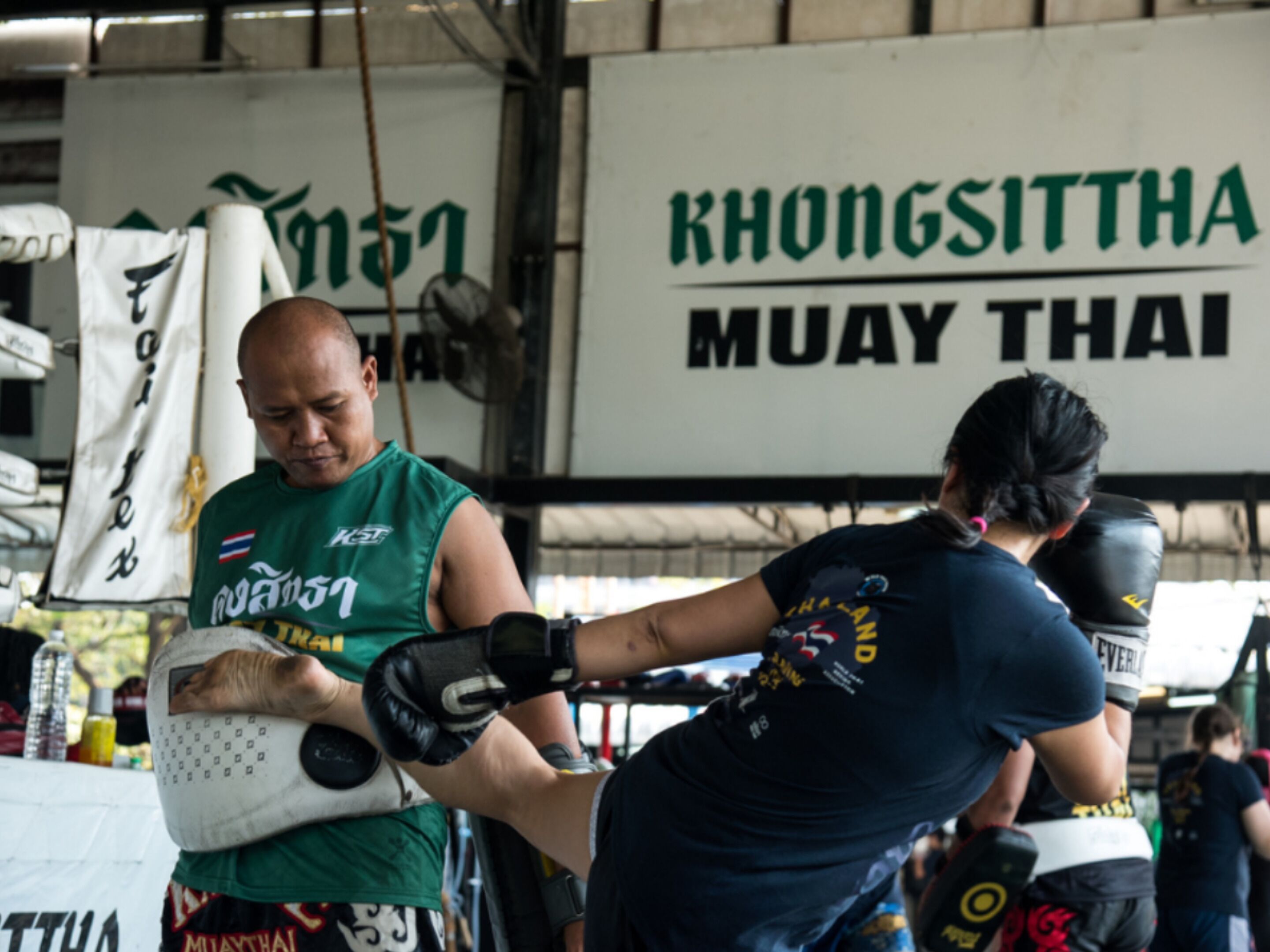 Una sesión de entrenamiento en un gimnasio con un letrero que dice 'KHONGSITTHA MUAY THAI'.