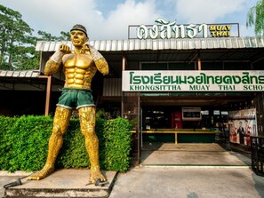 En Muay Thai-skola med en stor, gyllene staty av en kämpe framför ingången.