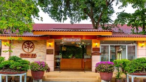The entrance of a hotel with a red tiled roof, a reception desk, and potted plants. - Kiatthada Resort (Bangkok)