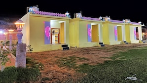 A row of yellow buildings with purple accents and a well-lit entrance. - The Kukas Resort (Amer)