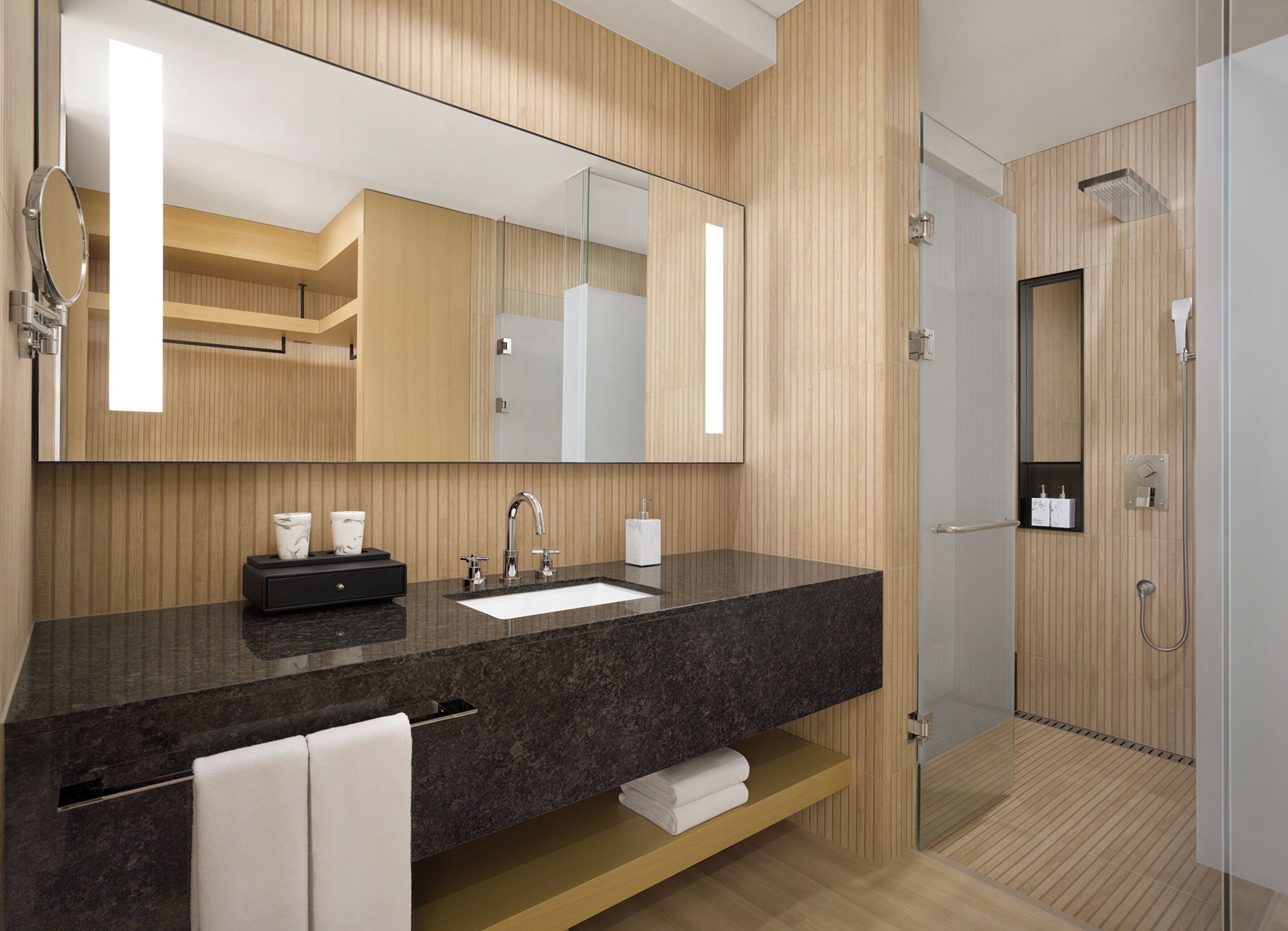 A modern bathroom with a large mirror, a sink, and a shower area.