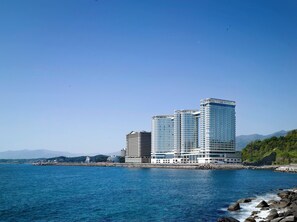 Un hotel de gran altura con varios pisos, cerca de una masa de agua y costas rocosas.