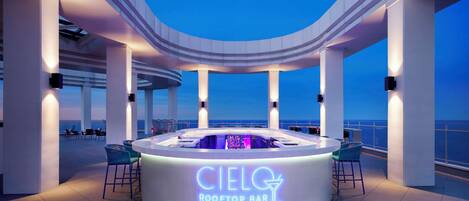Un bar en la azotea con un letrero de neón que dice 'Cielo Rooftop Bar' bajo un cielo despejado.