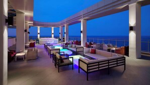 Un bar en la azotea con asientos y vistas al océano.