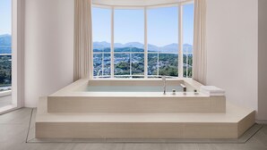 Un baño moderno con una bañera grande, vistas a un paisaje urbano y un techo curvo.