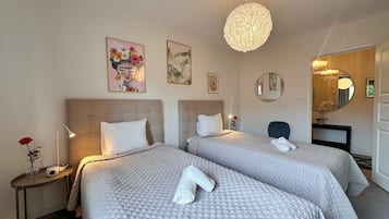 Ett hotellrum med två sängar, en rund kristallkrona och konstverk på väggarna.