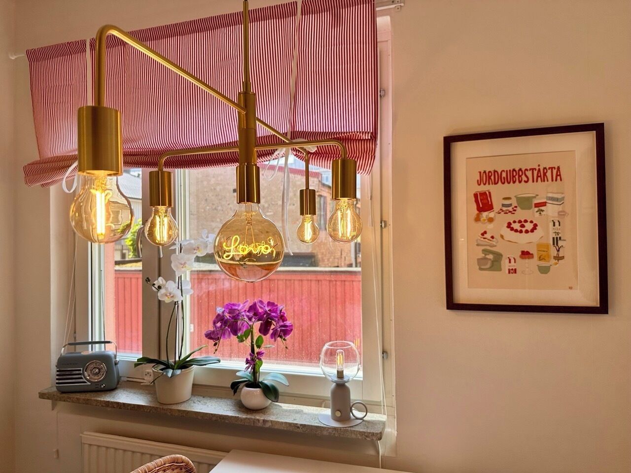 A kitchen with hanging light bulbs, a radio, and a framed picture on the wall.