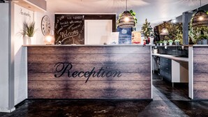 A reception area with a wooden reception desk labeled "Reception," a chalkboard with welcoming messages, and a modern interior design.